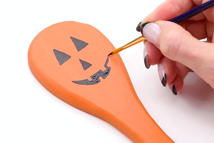 Hand painting a pumpkin face on a spoon (from onelittleproject.com)
