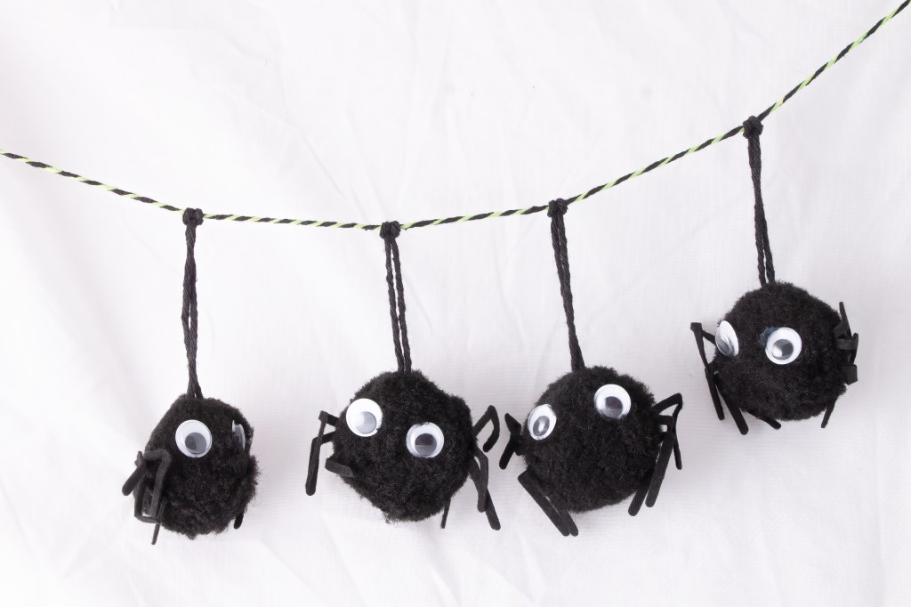 Googly Eyed Pom-pom spiders bunting isolated on white backdrop